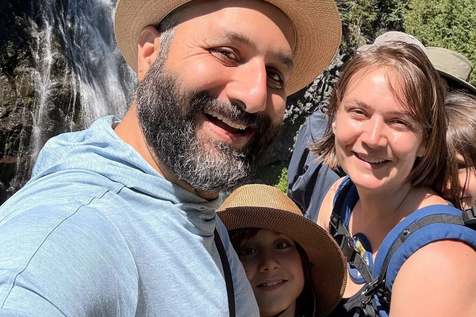 A selfie of all four of us in front of Narada Falls at Mount Rainier — Cy closest to the camera in a straw hat, Erika at the right, Big and Little between them.