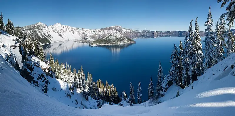 Crater Lake in winter, with the rim and trees buried under thick, deep snow.