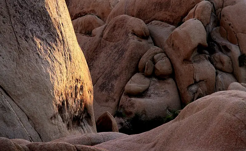 Large rounded tan granite boulders stacked in a pile along the Skull Rock Trail.