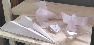 Five folded paper figures: a bird, a boat, a plane, a jumping frog and a crane.